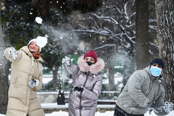 Прохожие играют в снежки на одной из улиц в Баку во время снегопада - Sputnik Азербайджан
