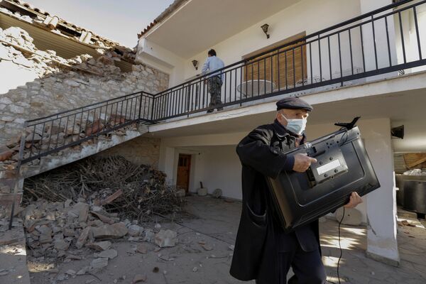Мужчина с телевизором у поврежденного дома вследствие землетрясения в Греции  - Sputnik Azərbaycan