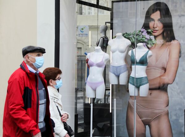 Люди в защитных масках проходят мимо магазина нижнего белья во время карантина в Ницце, Франция - Sputnik Азербайджан