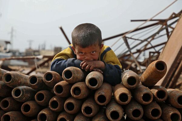 Ребенок на куче нейтрализованных снарядов на свалке металлолома города Маарет-Мисрин в  провинции Идлиб, Сирия - Sputnik Азербайджан