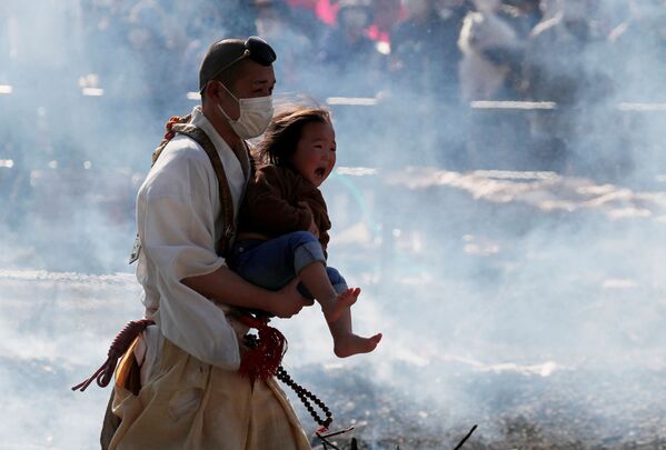 Буддийский монах несет плачущего ребенка во время фестиваля хождения по огню в Японии - Sputnik Азербайджан