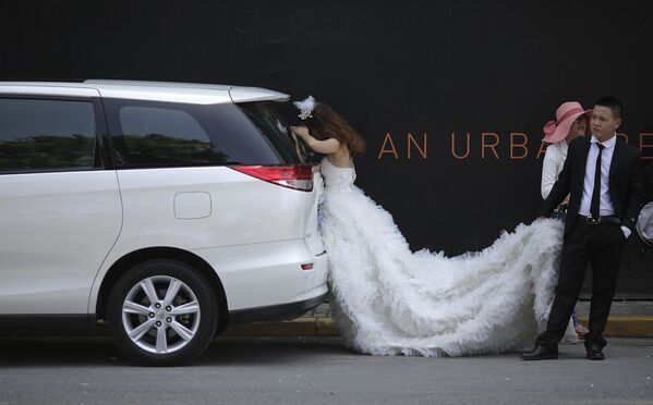 Невеста отдыхает в тени во время свадебной фотосессии в Шанхае    - Sputnik Азербайджан