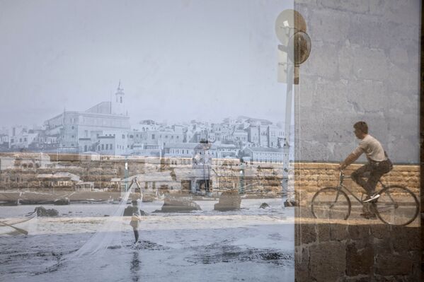 Мужчина на велосипеде отражается на старой фотографии Яффо, выставленной в окне, в районе Яффо в Тель-Авиве, Израиль - Sputnik Азербайджан