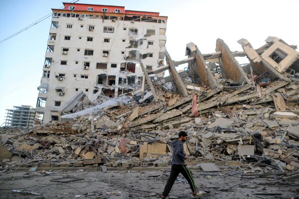 Палестинский мальчик проходит мимо руин здания, разрушенного в результате израильских авиаударов на фоне вспышки израильско-палестинского конфликта, Газа - Sputnik Azərbaycan