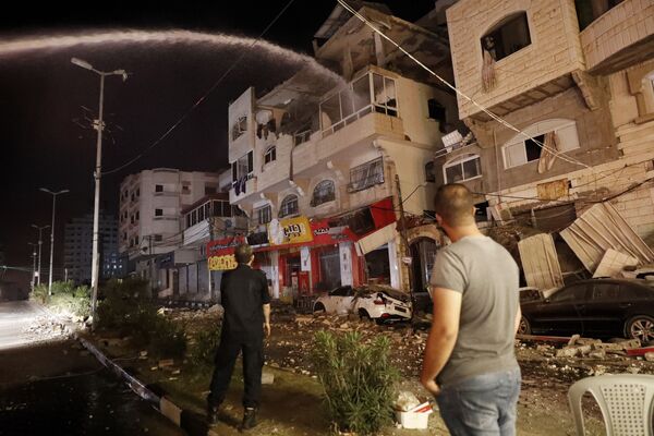 Пожарные тушат горящие жилые дома после того, как они пострадали от израильских авиаударов, в городе Газа - Sputnik Azərbaycan