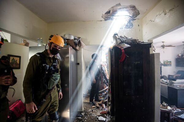 Солдаты работают у здания, поврежденного ракетой, запущенной из сектора Газа, в Ашдоде, на юге Израиля - Sputnik Azərbaycan