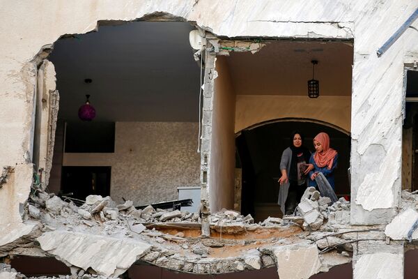Палестинцы осматривают свой дома, который был поврежден в результате израильского авиаудара, на фоне вспышки израильско-палестинского конфликта, в городе Газа - Sputnik Азербайджан