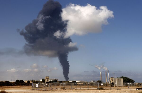 Шлейф дыма от бушующего пожара на нефтехимическом складе вздымается на нефтехранилище, пораженном ракетами ХАМАС в городе Ашкелон - Sputnik Азербайджан