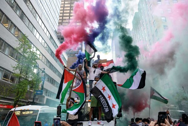 Демонстранты держат палестинский и сирийский флаги в поддержку Палестины в центре Манхэттена - Sputnik Азербайджан