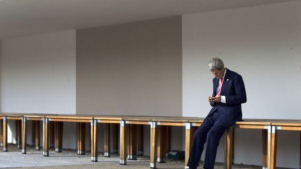Бывший госсекретарь США Джон Керри проверяет свой мобильный телефон перед встречей на третий день переговоров по ядерной программе Ирана в отеле Intercontinental в Женеве, 9 ноября 2013 - Sputnik Азербайджан