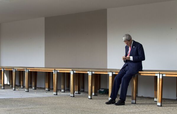 Бывший госсекретарь США Джон Керри проверяет свой мобильный телефон перед встречей на третий день переговоров по ядерной программе Ирана в отеле Intercontinental в Женеве, 9 ноября 2013 - Sputnik Азербайджан