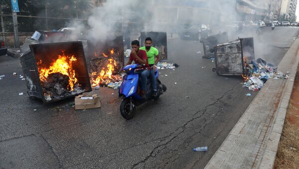 Двое мужчин проезжают мимо горящих мусорных баков в Бейруте  - Sputnik Азербайджан