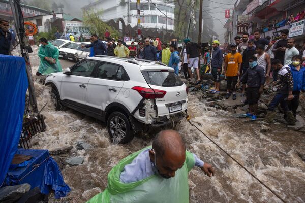 Люди пытаются вытянуть автомобиль, поврежденный во время наводнений после сильных муссонных дождей в Индии - Sputnik Азербайджан