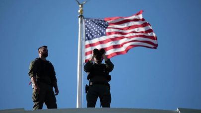 Американские военный с биноклем рядом с флагом США