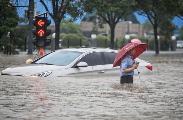 Мужчина у затопленной в результате проливных дождей машины после проливных дождей в Чжэнчжоу в центральной провинции Китая Хэнань - Sputnik Azərbaycan