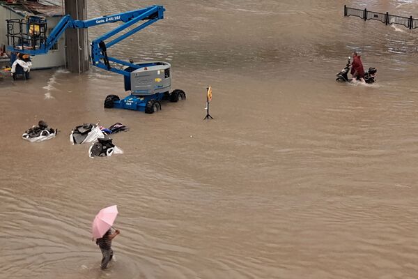 Люди идут по затопленным улицам после проливных дождей в Чжэнчжоу в центральной провинции Китая Хэнань - Sputnik Azərbaycan