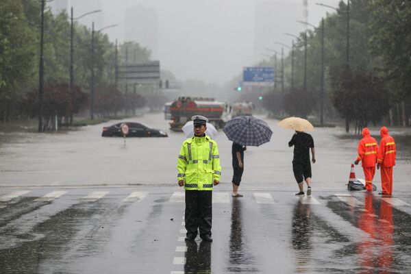 Офицер полиции на переходе затопленной улицы после проливных дождей в Чжэнчжоу в центральной провинции Китая Хэнань - Sputnik Azərbaycan