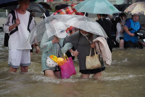Люди идут по затопленной улице в Чжэнчжоу, провинция Хэнань, Китай - Sputnik Azərbaycan