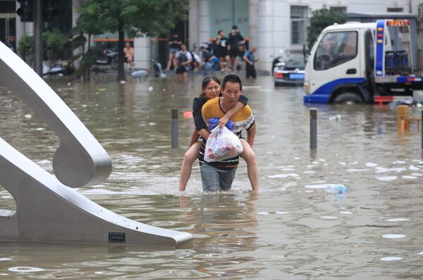 Мужчина несет женщину на спине по затопленной дороге в Чжэнчжоу, Китай  - Sputnik Azərbaycan