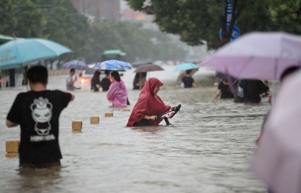 Люди идут по затопленным улицам после проливных дождей в Чжэнчжоу в центральной провинции Китая Хэнань  - Sputnik Azərbaycan