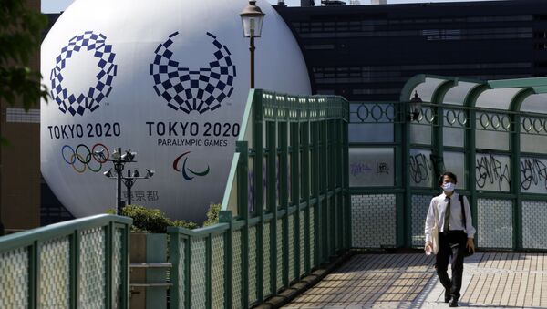 Мужчина проходит перед инсталляцией Олимпийских и Паралимпийских игр в Токио-2020 - Sputnik Azərbaycan