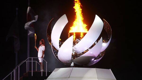 Наоми Осака из Японии держит олимпийский факел после зажжения олимпийского котла на церемонии открытия  - Sputnik Азербайджан