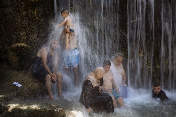 Израильские арабы стоят под водопадом во время мусульманского праздника Курбан-байрам в национальном парке Ган-ха-Шлоша - Sputnik Азербайджан