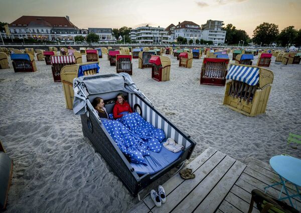 Две девушки готовятся провести ночь в специально разработанном шезлонге на пляже Балтийского моря в Травемюнде, Германия - Sputnik Азербайджан