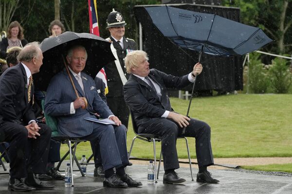 Британский принц Чарльз и премьер-министр Борис Джонсон укрываются от дождя во время открытия Мемориала полиции Великобритании в Национальном мемориальном дендрарии в Олревасе, Англия. - Sputnik Азербайджан
