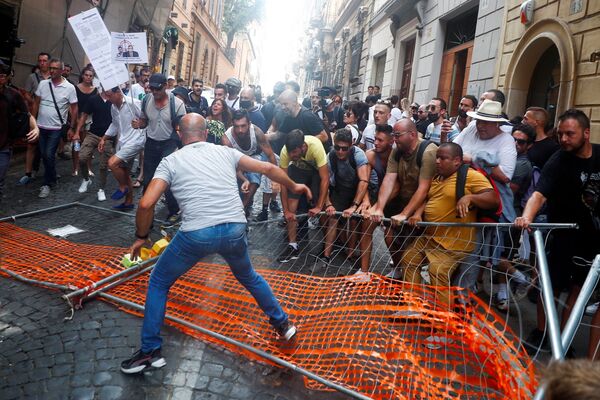 Протестующие снимают барьер, установленный полицией, во время демонстрации против плана Green Pass в Риме, Италия. - Sputnik Азербайджан