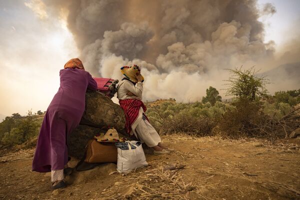 Женщины на горной дороге со своими вещами во время лесных пожаров на севере Марокко . - Sputnik Азербайджан