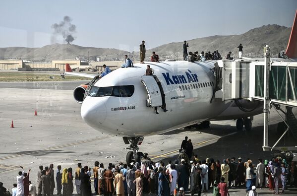 Афганцы забираются на самолет в аэропорту после вступления талибов в Кабул. - Sputnik Азербайджан