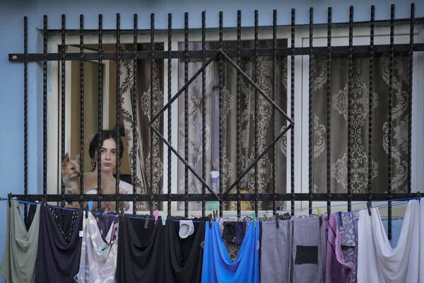 Женщина в окне смотрит спектакль на открытом воздухе в Бухаресте, Румыния. - Sputnik Азербайджан