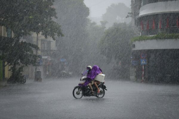 Люди едут на скутере под проливным дождем в Ханое, Вьетнам. - Sputnik Азербайджан