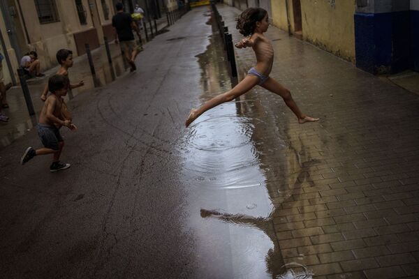 Дети прыгают по лужам во время дождя в Барселоне, Испания. - Sputnik Азербайджан