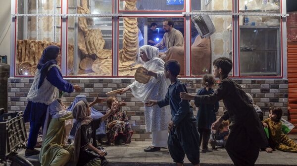 Женщина раздает хлеб нуждающимся детям перед пекарней в Кабуле - Sputnik Азербайджан
