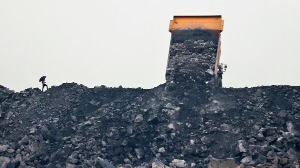 Рабочий наблюдает, как уголь выгружается из грузовика  - Sputnik Azərbaycan