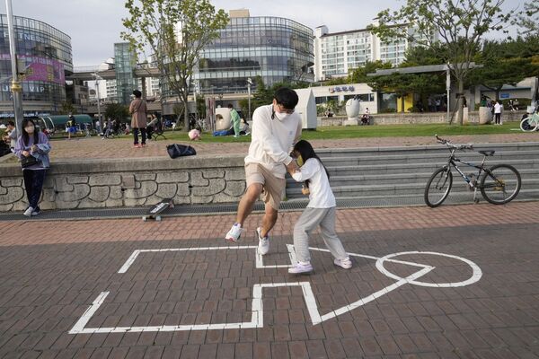 Сон Кван Чже и его дочь Чжэ Ин играют в оригинальную &quot;Игру в кальмара&quot; в парке в Кояне, Южная Корея. - Sputnik Азербайджан