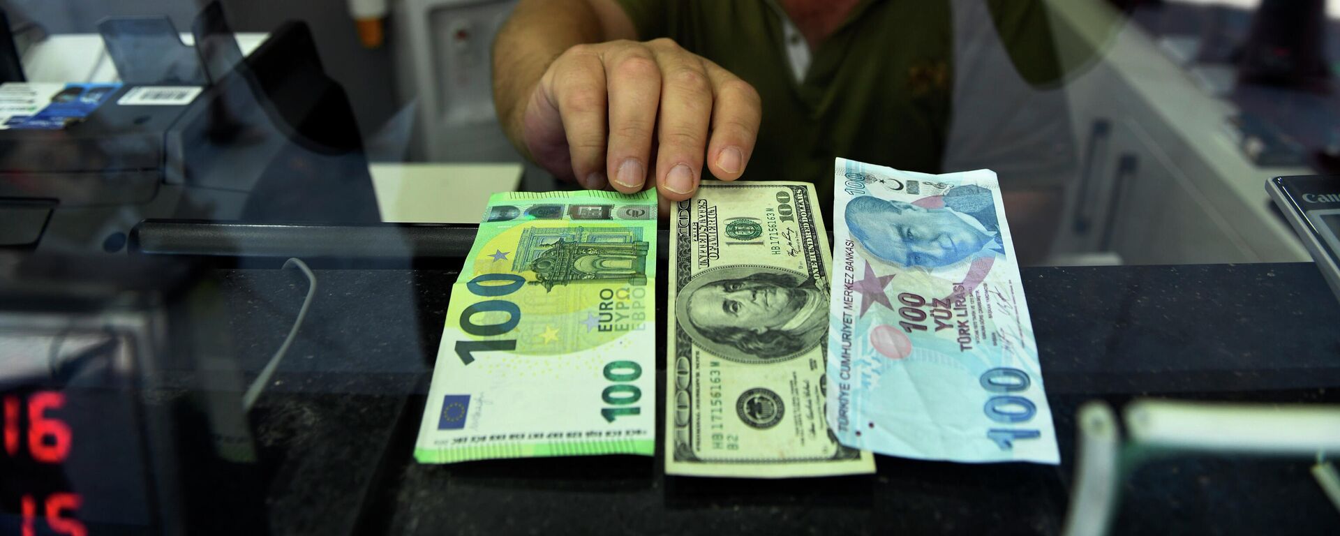 Сотрудник пункта обмена валюты показывает банкноты 100 евро, 100 долларов США и 100 турецких лир, фото из архива - Sputnik Азербайджан, 1920, 08.06.2023