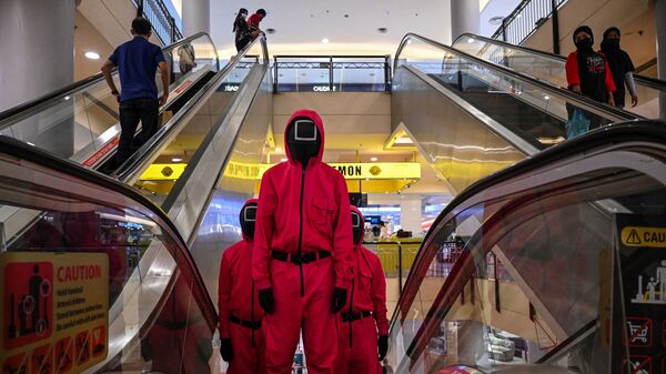 Косплееры в костюмах персонажей из сериала Netflix Игра в кальмара на эскалаторе в торговом центре Куала-Лумпура, Малайзия - Sputnik Азербайджан