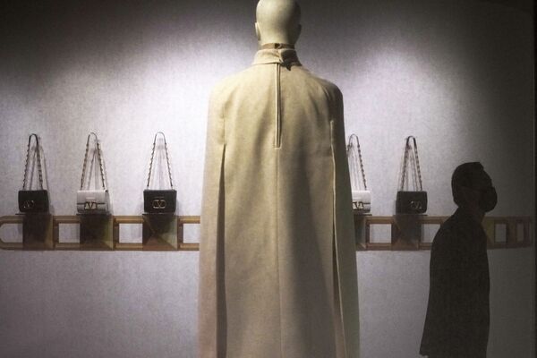 Мужчина в маске проходит мимо коллекции Valentino, представленной на выставке Valentino Re-Signify в торговом центре в Пекине, Китай. - Sputnik Азербайджан