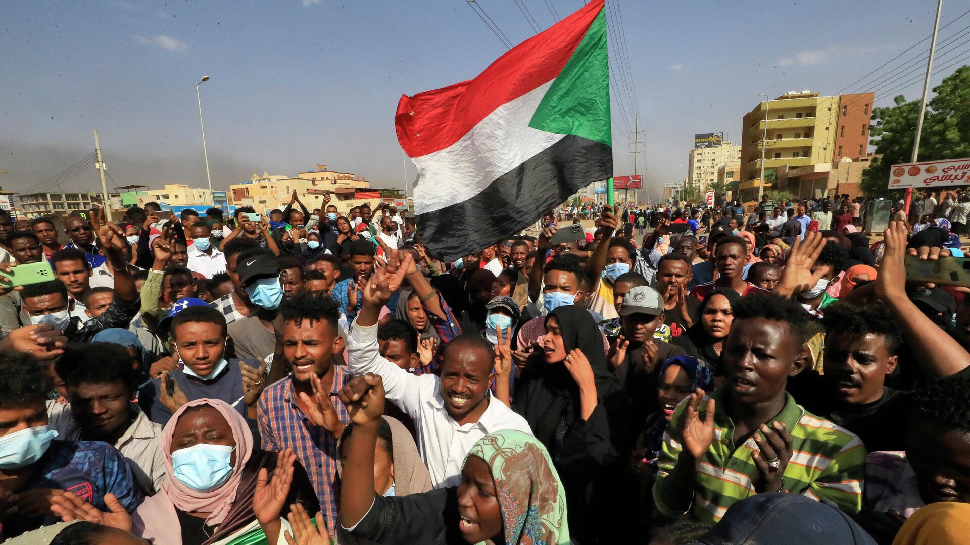 Суданские протестующие поднимают национальные флаги во время митинга в столице Хартуме - Sputnik Азербайджан, 1920, 25.10.2021