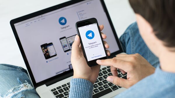 Мужчина использует приложение Telegram на iPhone - Sputnik Azərbaycan