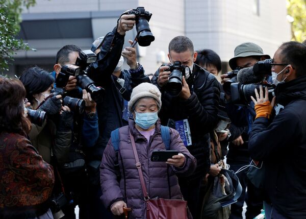 Фотографы снимают женщину, которая смотрит прямую трансляцию пресс-конференции японской принцессы Мако и ее мужа Кей Комуро. - Sputnik Азербайджан