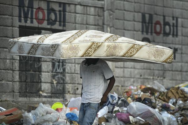 Мужчина идет с матрасом на голове в Порт-о-Пренсе, Гаити. - Sputnik Азербайджан