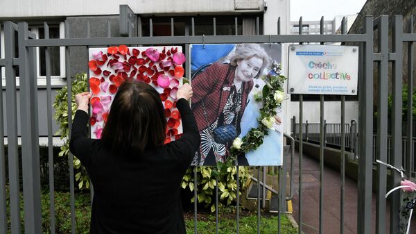 Женщина помещает фотографию Мирей Кнолль на заборе вокруг своего дома в Париже, 27 марта 2108 года - Sputnik Азербайджан