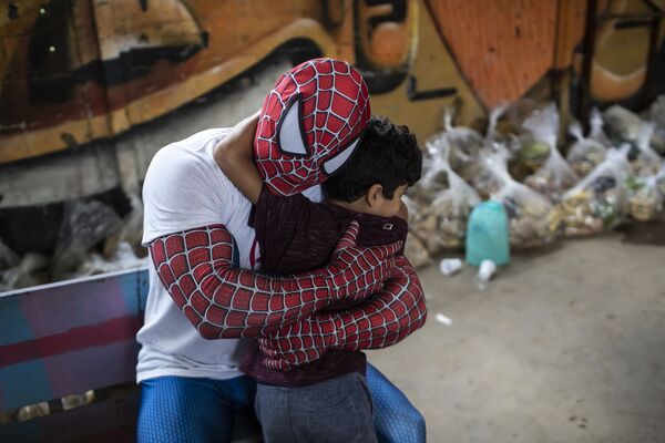 Волонтер в костюме Человека-паука обнимает ребенка в Рио-де-Жанейро, Бразилия. - Sputnik Азербайджан