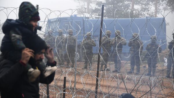 Польские военнослужащие возле заграждения из колючей проволоки у лагеря нелегальных мигрантов на белорусско-польской границе - Sputnik Азербайджан