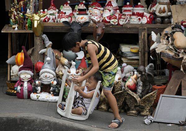 Дети играют рядом с рождественскими украшениями, которые продаются на улице в Маниле, Филиппины. - Sputnik Азербайджан