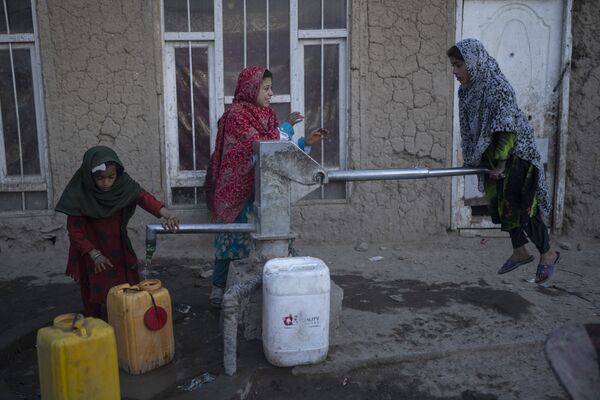 Девочки наполняют контейнеры водой с помощью ручного насоса в лагере для беженцев в Кабуле, Афганистан. - Sputnik Азербайджан